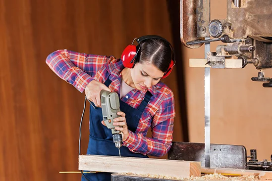Person bohrt mit Bohrmaschine in Holz